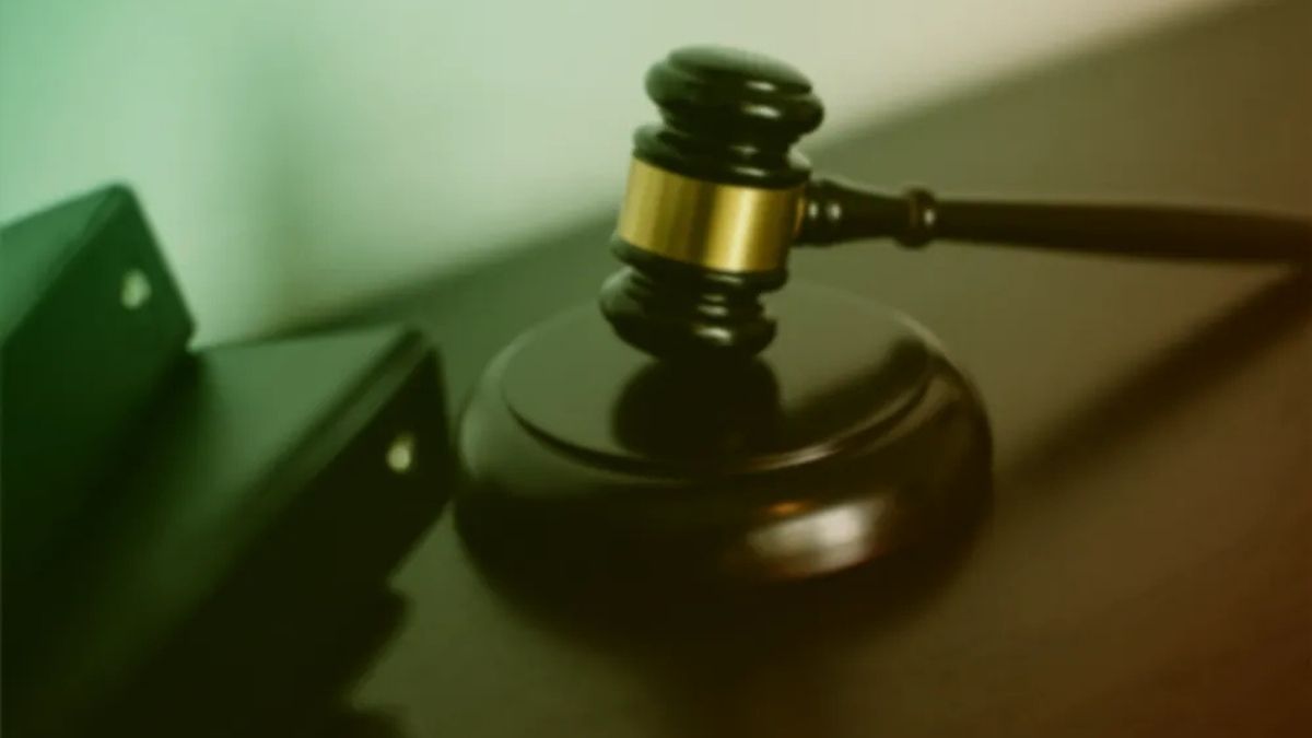 A judge's gavel resting on a sound block beside a file folder, in warm green and orange light.