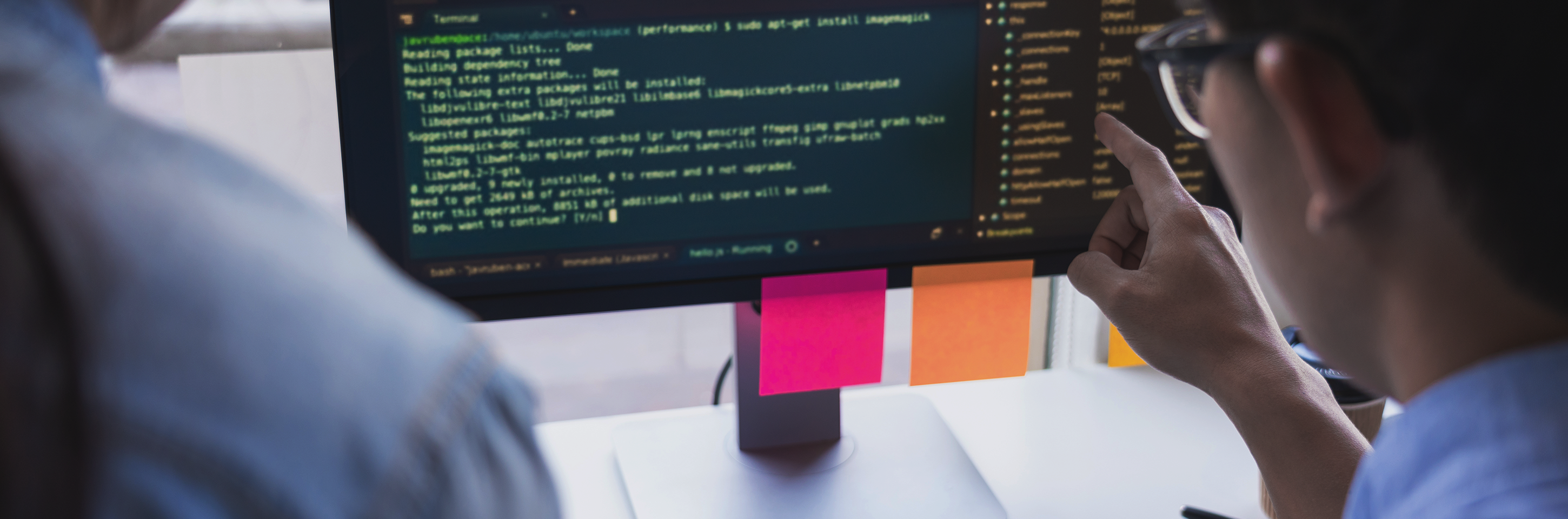 People looking at computer code on monitor