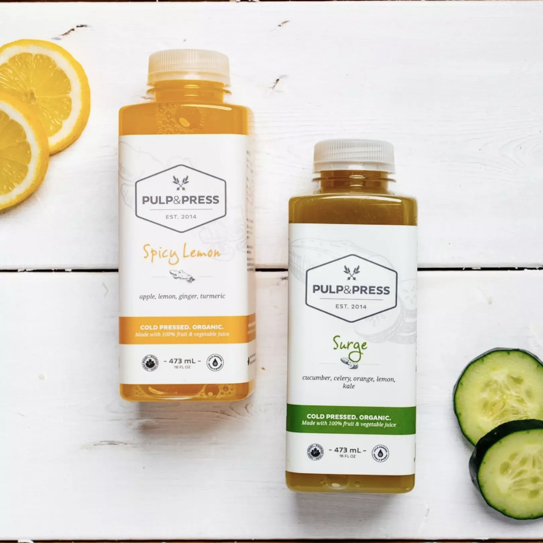 Pulp &amp; Press juices on a white table with lemon and cucumber slices