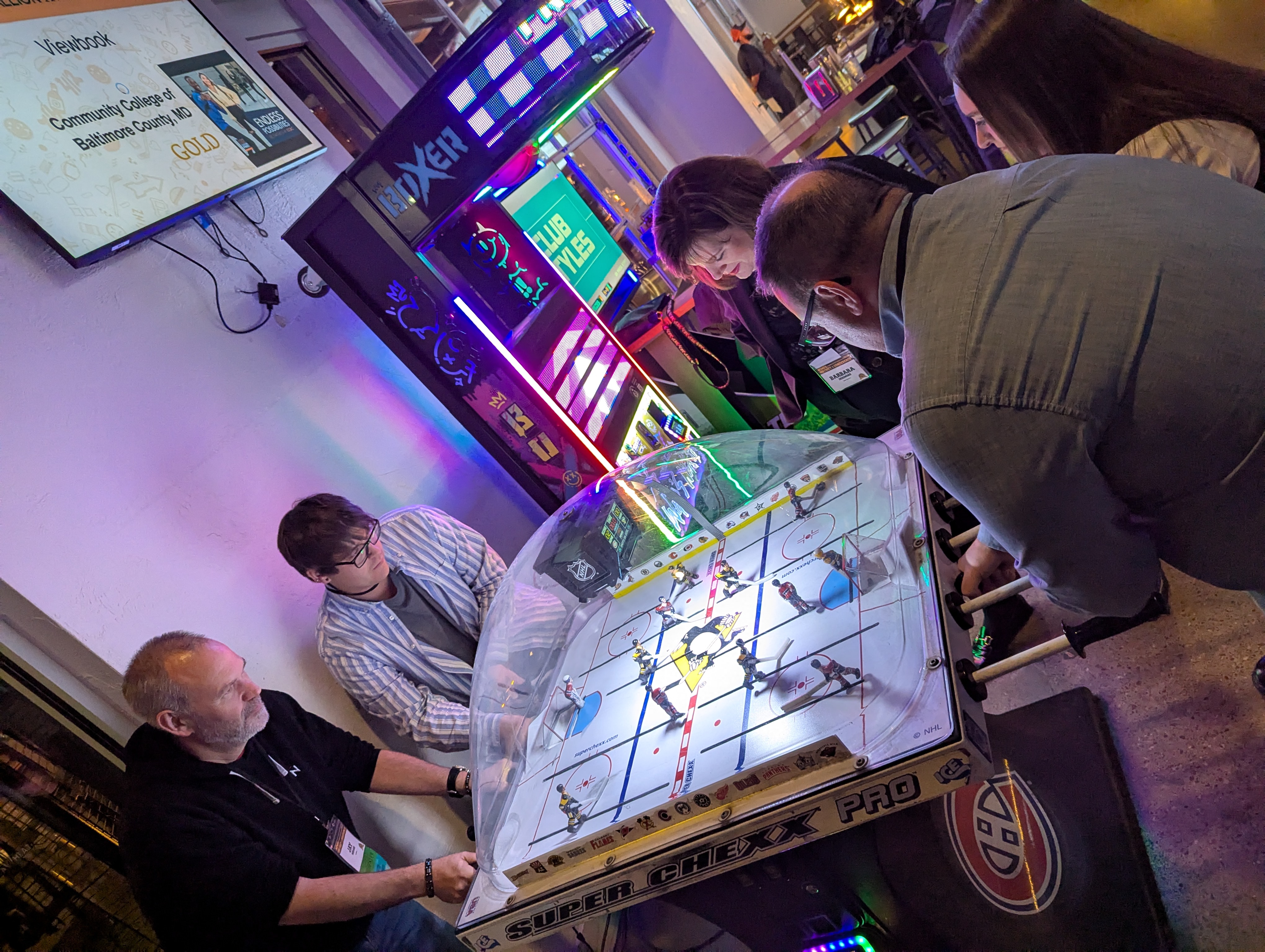 Jay Menard of Northern and conference attendees playing an arcade hockey game during downtime at the NCMPR conference