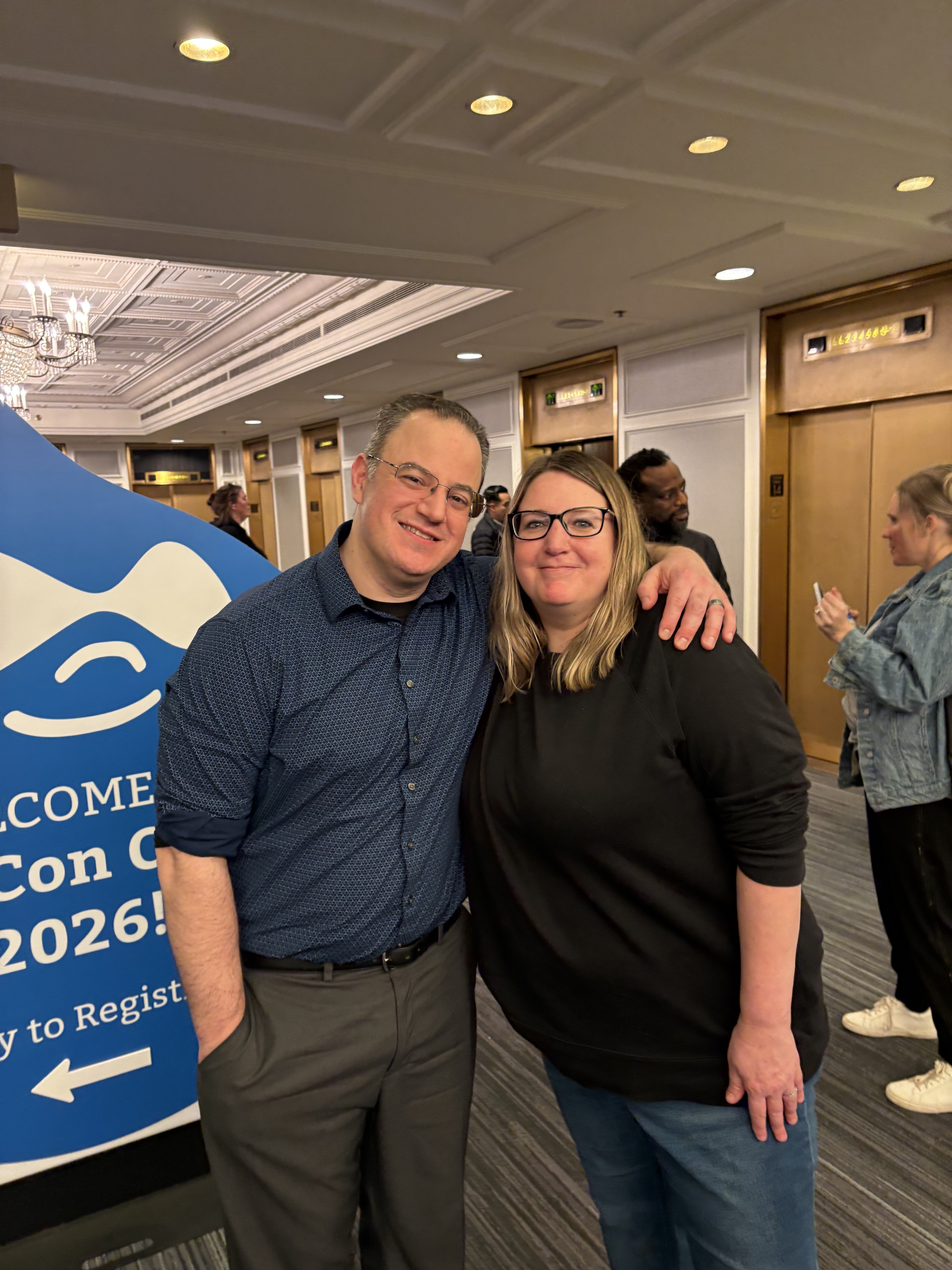 Steve Erwin from Tompkins Cortland Community College and Christine Saunders from Northern smiling together at DrupalCon 2026, with a Drupal welcome sign visible in the background.