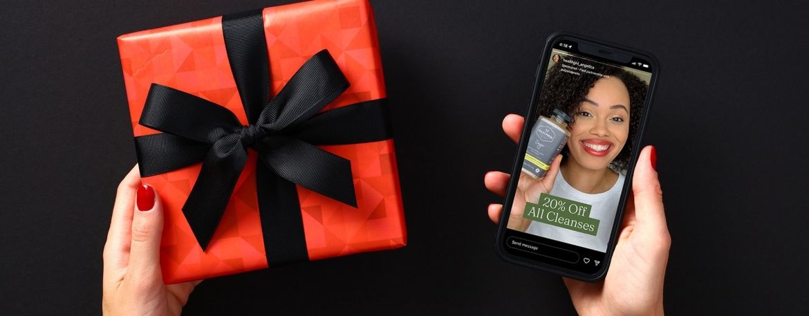 A gift in the left hand with a phone in the right hand.