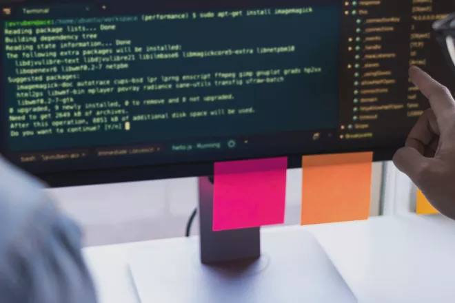 People looking at computer code on monitor