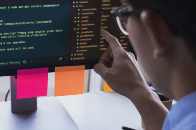 People looking at computer code on monitor