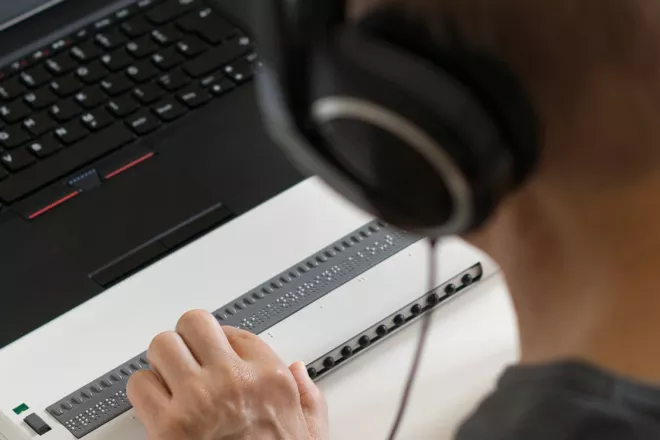 A person in fornt of a laptop wearing headphones