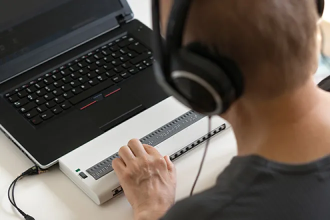 A person wearing headphones in front of a laptop 