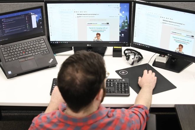 Man working on laptop with multiple screens