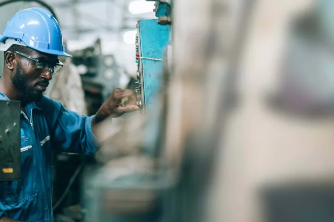 Man working on a machine wearing a safety helmet