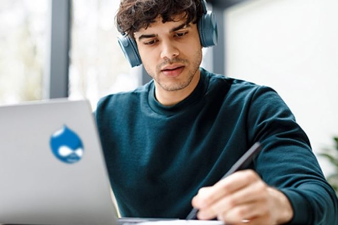 Student working on laptop with a Drupal sticker