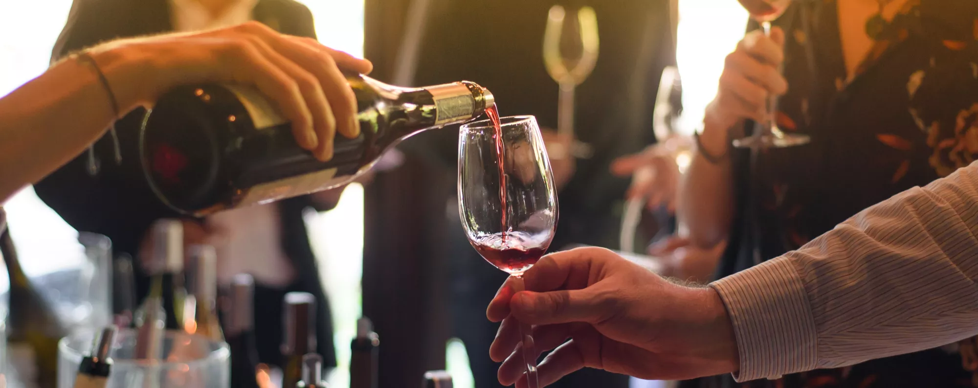 a glass of red wine being poured into a persons glass enjoying a wine tasting session