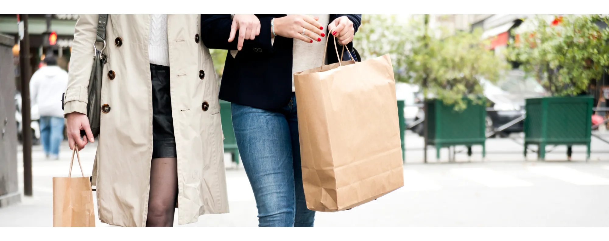 Two people holding hands and holding shopping bags while walking