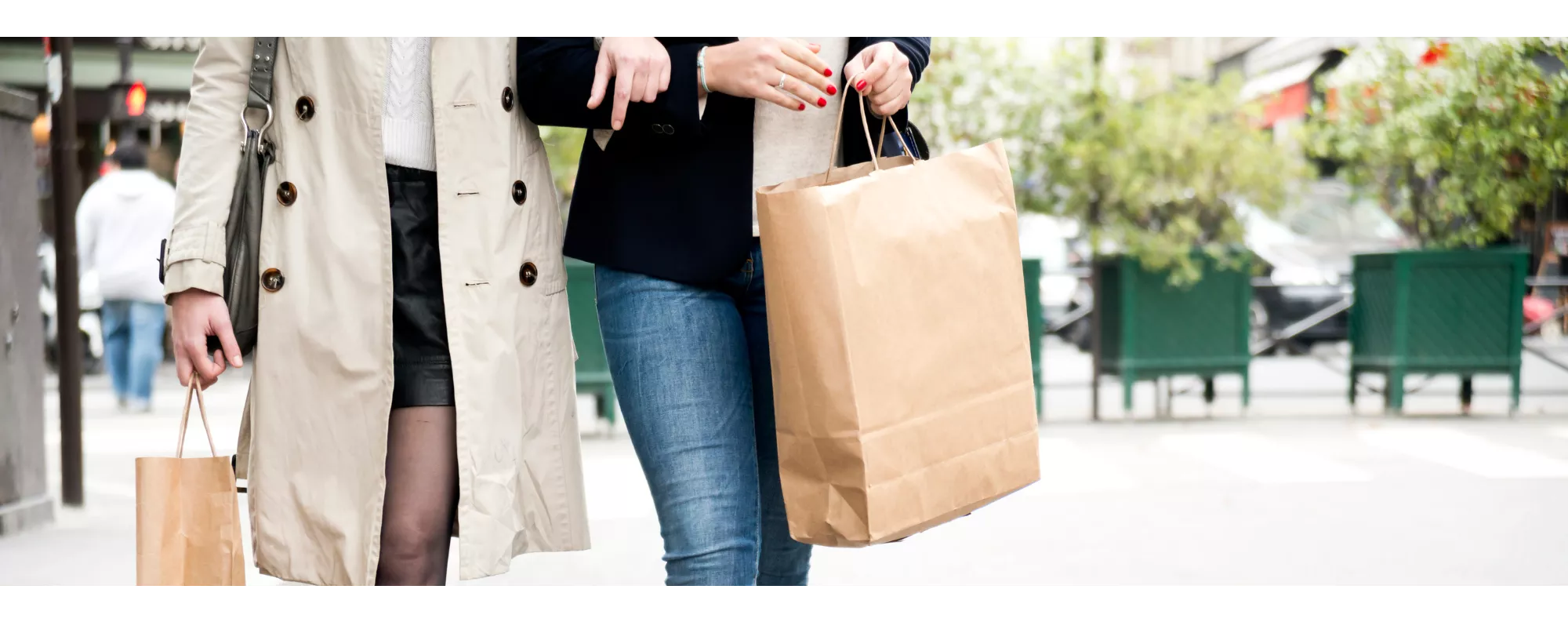 Two people holding hands and holding shopping bags while walking