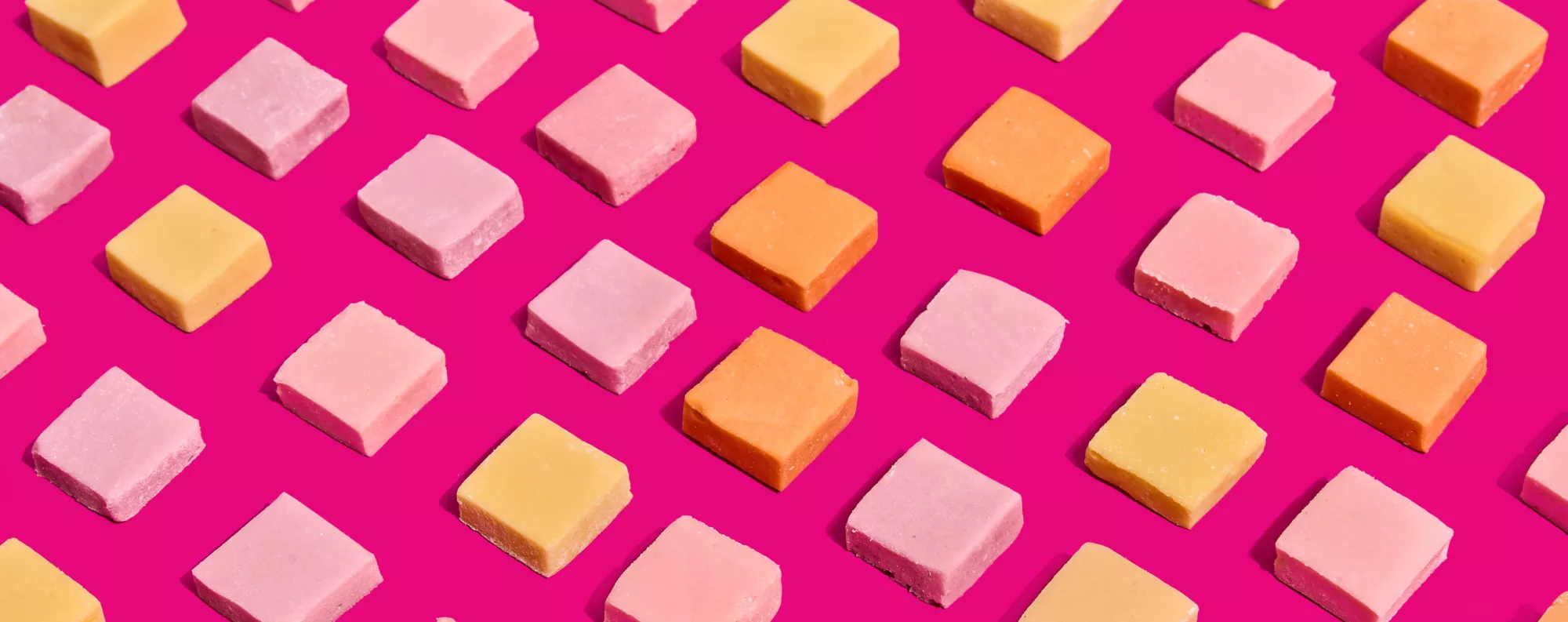 Protein Candy squares in rows on a pink background