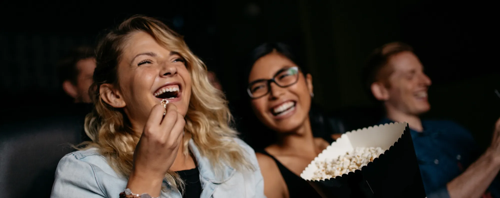 People laughing watching a movie and eating popcorn