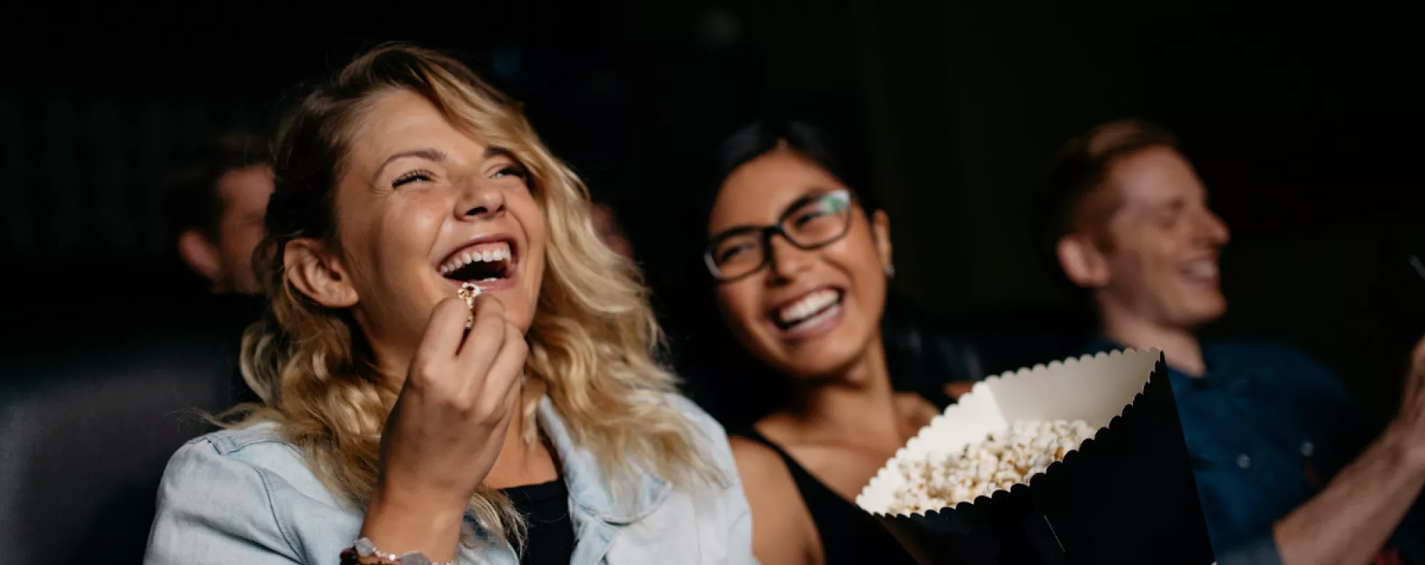 People laughing watching a movie and eating popcorn