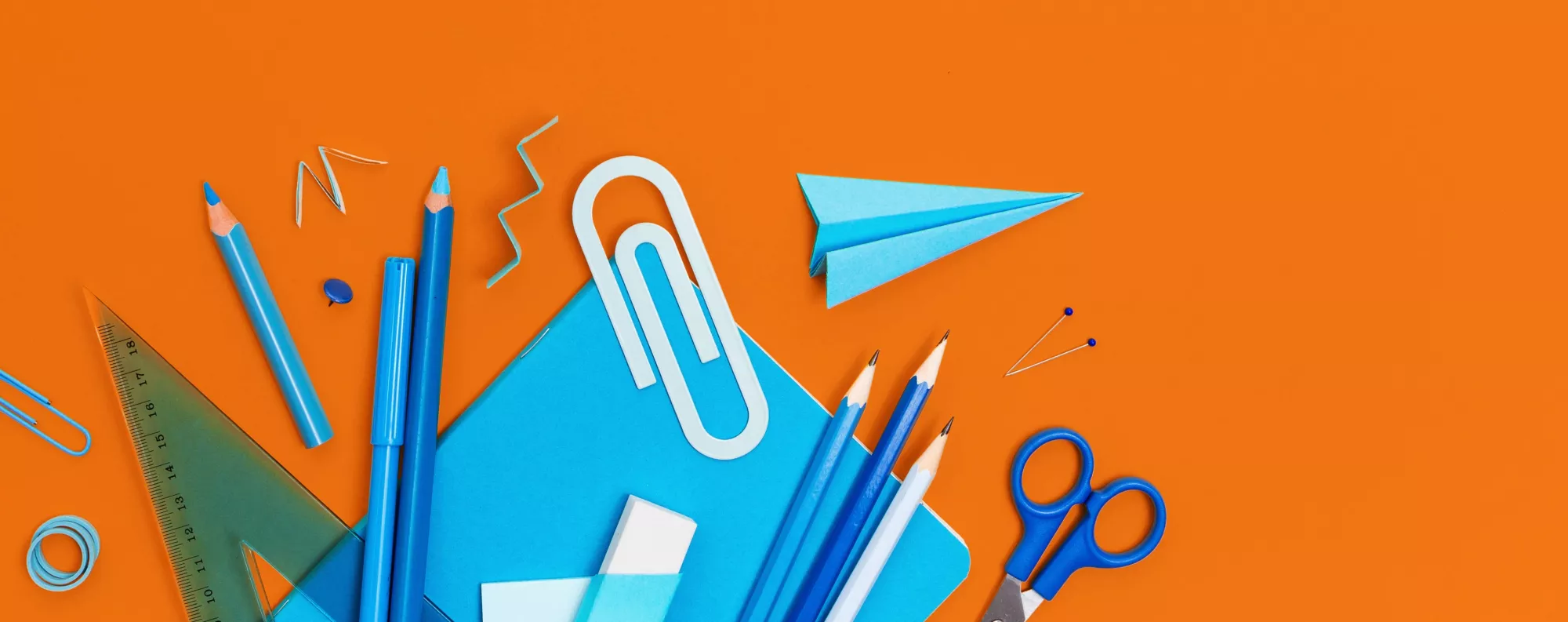 top down view of office supplies scattered on an orange surface