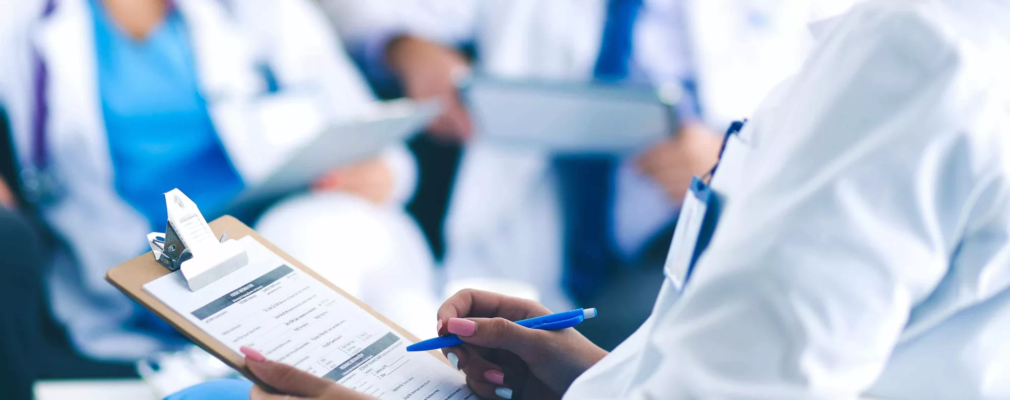 Medical professional filling out form on clipboard.