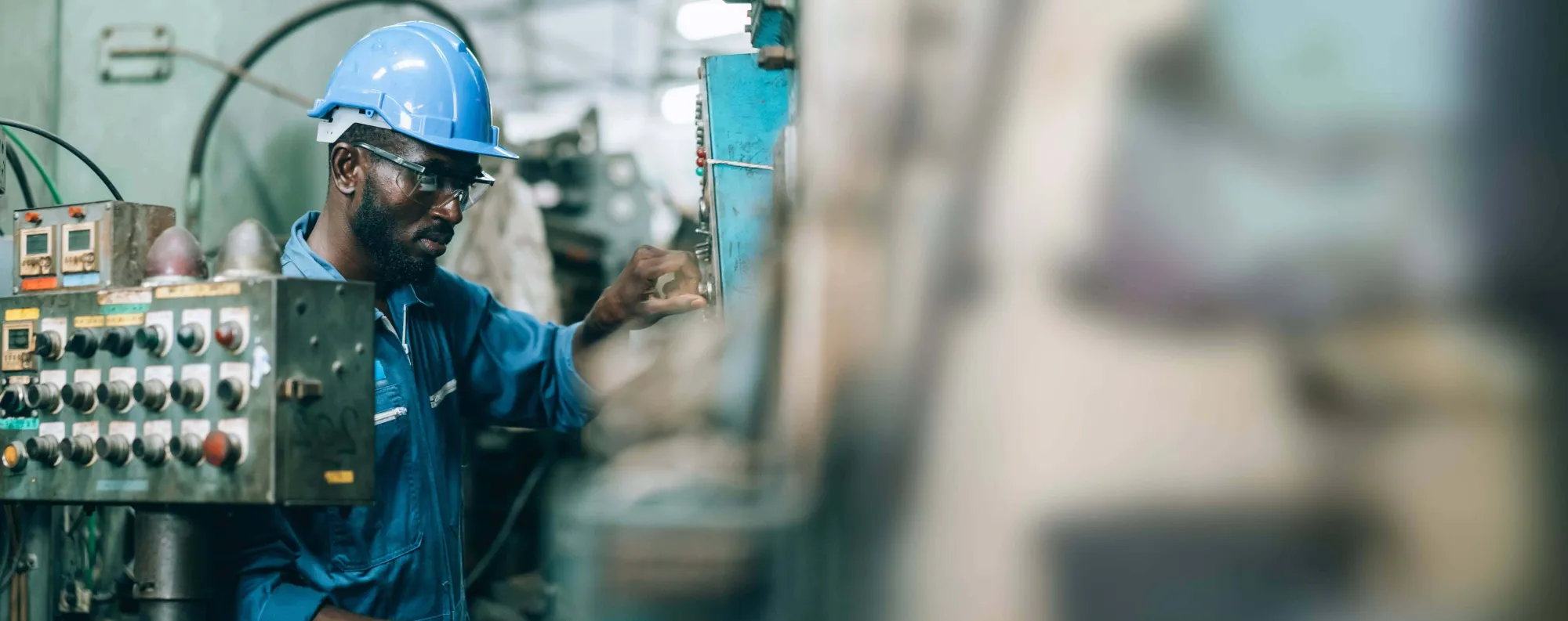 Man working on a machine wearing a safety helmet