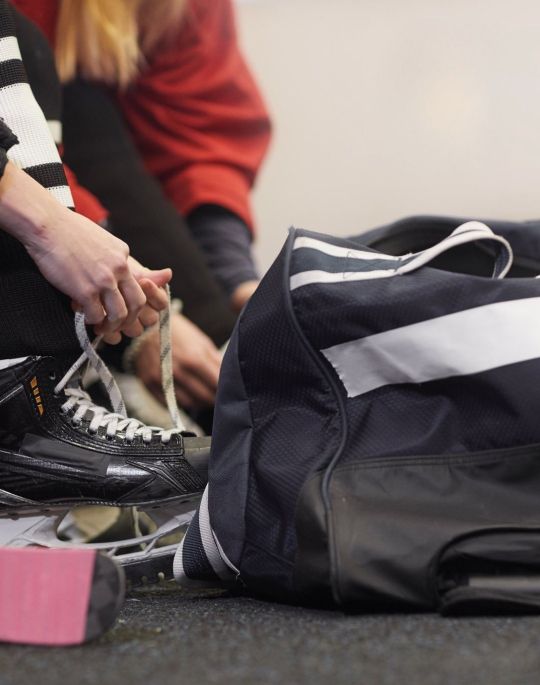 Person tying skates with Gongshow Gear logo.