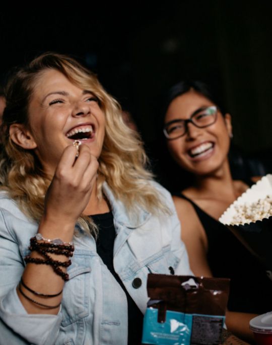 People laughing watching a movie and eating popcorn
