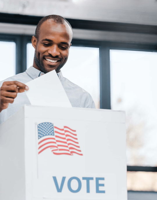 A man dropping a ballot into a ballot box.