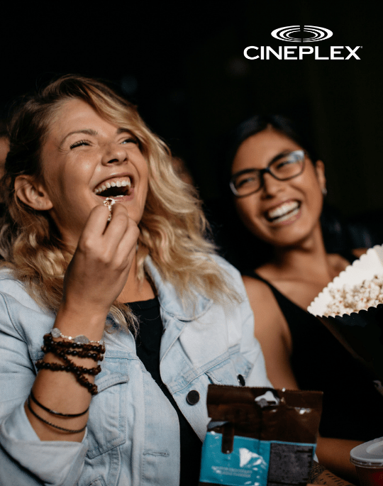 People laughing watching a movie and eating popcorn