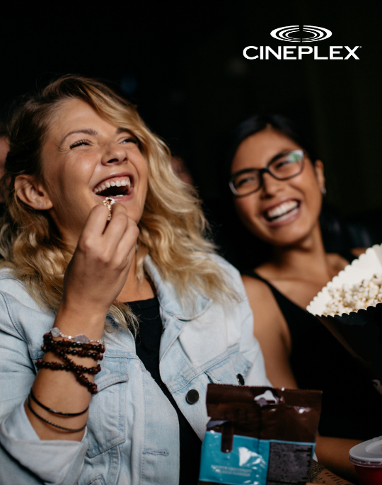 People laughing watching a movie and eating popcorn