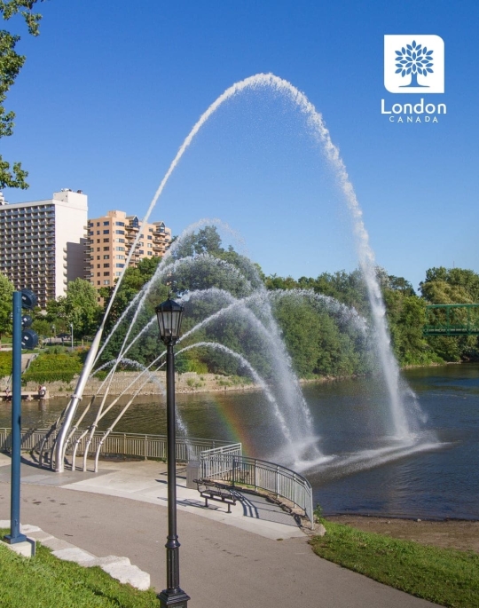 Water fountain over a river with city behind