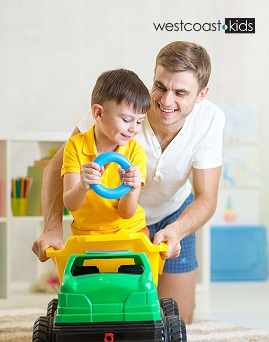 father playing with son riding on a toy truck